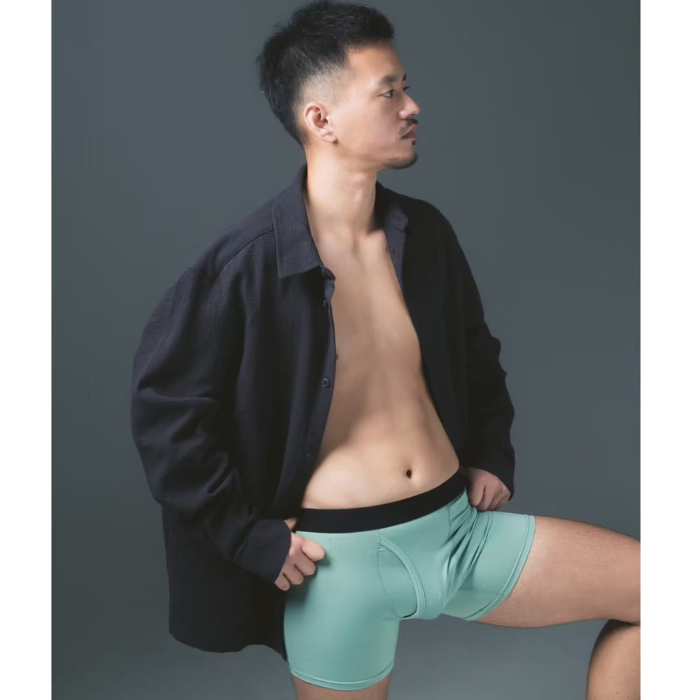 スモークグリーンのFTMボクサーパンツを着用し、横を向いている人物の写真（Side view of a person looking to the side wearing Smoke Green FTM boxer briefs）